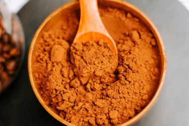 Kakao tozu, ahşap bir kasede, karanlık bir yüzey üzerinde bir kaşıkla mutfak düzeninde.