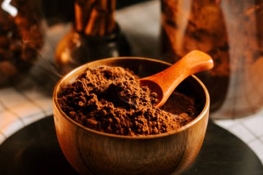 Kakao tozu ahşap bir kasede, masada cam kavanozların yanında durur.