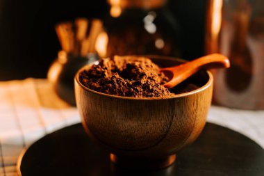 Kakao tozu bir kaşıkla ahşap bir kasede otururken arka plan nesneleri odak dışı kalır.