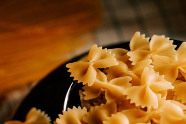 Mutfak ortamında ahşap arka planda düzgünce yerleştirilmiş farklı makarna türleri.