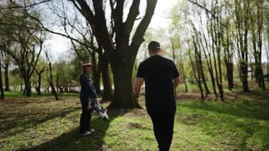 Erkekler ve kadınlar bahar parkında çiçeklerle ağaçların altında pikniğin tadını çıkarırlar.