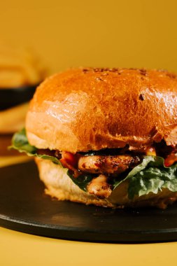 Sarı arka planda marullu sulu burger öğle yemeği ya da atıştırmalık zamanı.