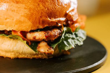 Sulu burger, parlak sarı arkaplanlı basit bir tabakta servis edilir.