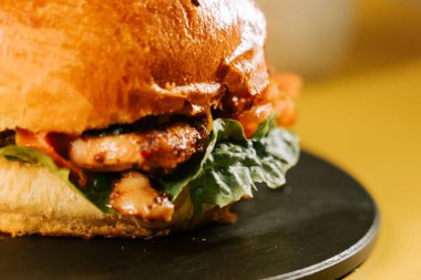 Parlak sarı arka planda taze malzemeli sulu hamburger.