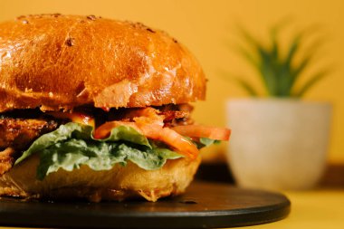Sarı arka planda taze malzemelerle sulu hamburger yemek için hazır.