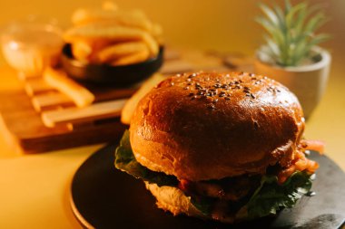 Sulu burger, yanında patates kızartması ve sarı bir tabakta servis edilir.