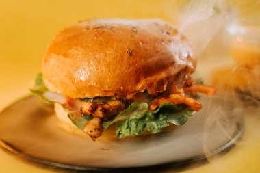 Taze burger, yerel bir lokantada açık sarı arka planda bir tabakta duruyor.