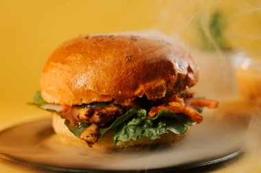 Sulu burger, yemek saatinde sarı arka planda yemeye hazır.