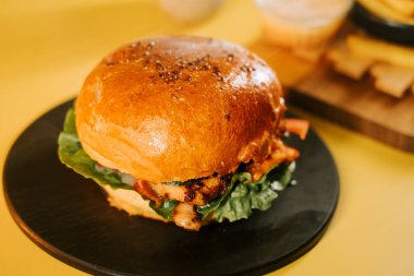 Güneşli bir günde, sarı bir arka planda sulu bir burgerin tadını çıkarıyorum.