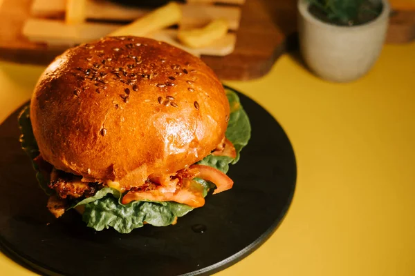 Sulu burger, sarı arka planı ve patates kızartması olan bir tabakta servis edilir.