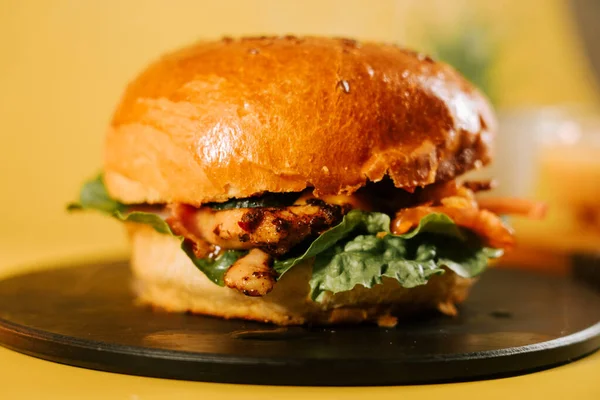Sulu burger ve taze malzemeler sarı arka planda, basit bir ortamda.