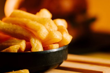 Sıcak bir restoranda öğle yemeği sırasında siyah bir tabakta taze patates kızartmasının tadını çıkarıyorum.