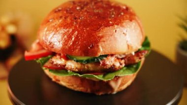 Salatalı, domatesli ve soslu hamburger basit bir tabakta servis edilir.