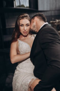 Çiftler resmi giyinip gece özel bir mekanda sıcak bir kucaklaşmayla poz verirler.