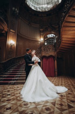 Büyük bir salonda dans eden çift büyük bir merdiven ve ahşap duvarlarla bir düğün sırasında