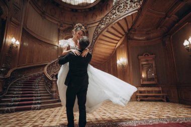 Düğün töreninde çift büyük binada zarif merdivenlerle dans ediyor.