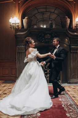 Özel bir etkinlik sırasında zarif detaylarla süslenmiş büyük bir salonda çift dans ediyor.