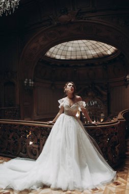 Gelinlikli kadın, zarif mimarisi ve yumuşak ışıklandırmasıyla tarihi binada poz veriyor.