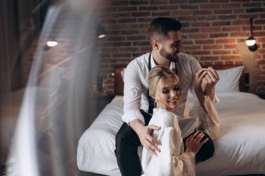 Çift, yatağın yanındaki şık bir otel odasında hoş vakit geçirmek ister.