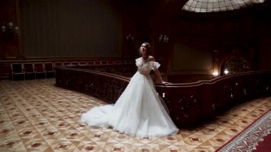 Gelin, özel bir olay sırasında tarihi binanın içinde şık bir elbiseyle poz veriyor.