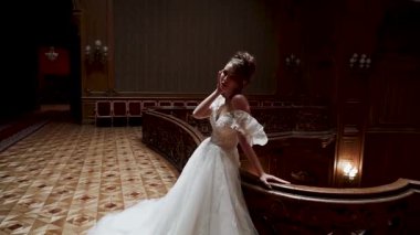 Model, bir moda etkinliği sırasında büyük bir salonda, merdivenlerde bir elbisenin içinde poz verir.