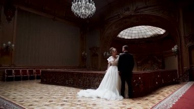 Çift, düğün töreninde büyük salonda avizeyle yan yana durur.