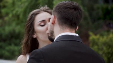 Baharın güneşli bir gününde çift parkta öpüşüyor.