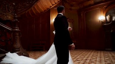 Bir çift düğün töreninde tarihi binada zarif merdivenlerden aşağı iniyor.