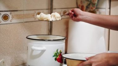 Kadın evde yemek hazırlarken mutfak ortamında brokoli pişiriyor.