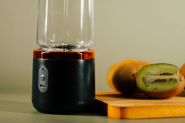 Meyve suyu hazırlamak için kivilerle birlikte bir masada taşınabilir blender yerleştirildi