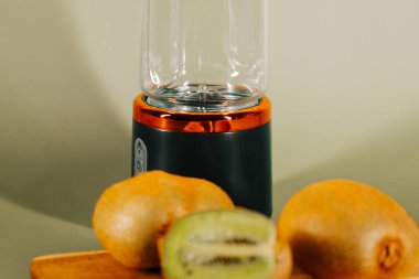 Tahta kesme tahtasının üzerinde kiwifruit ile meyve suyu yapmak için taşınabilir blender