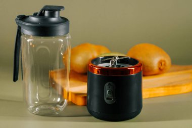 Kesme tahtasındaki taze meyvelerle evde smoothie yapmak için taşınabilir blender