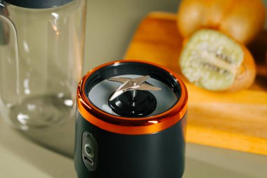 Taşınabilir blender yakınlarda meyveli bir masada oturuyor ve meyve suyu yapmaya hazır.