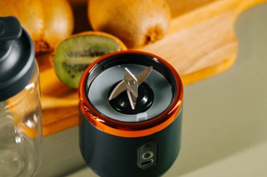 Evde taze meyveli ahşap tezgahta meyve suyu yapmak için taşınabilir blender.