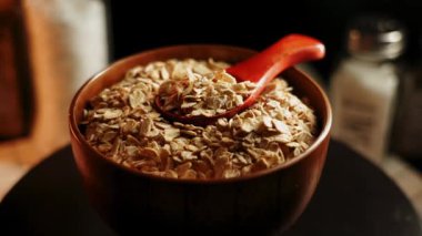 Mutfak masasında kırmızı kaşıkla ahşap bir kasede yulaf ezmesi yapmak.