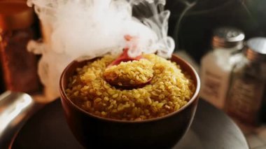 Etrafında baharat ve malzemelerle sıcak bir mutfak ortamında bulgur pişirme işlemi