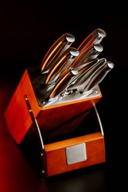 Gece vakti karanlık bir yüzeyde bıçak bloğu ve çoklu mutfak bıçakları.