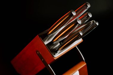 Mutfak bıçakları ahşap blokta sıcak ışıklandırma ve karanlık arka plan sahneleriyle