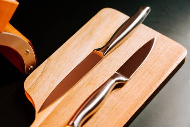 Mutfak ortamında tahta kesme tahtasına yerleştirilmiş iki mutfak bıçağı.
