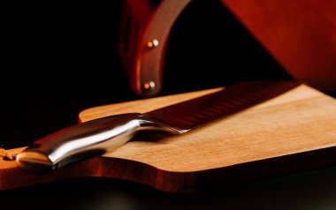 Akşam ışığında mutfak ortamında tahta kesme tahtasının üzerinde duran bıçak.