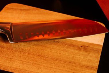 Keskin bıçak ahşap kesme tahtasına dayanıyor. Mutfakta yemek hazırlığı için hazır.