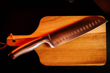 Akşam vakti mutfak ortamında tahta kesme tahtasında keskin bir bıçak.