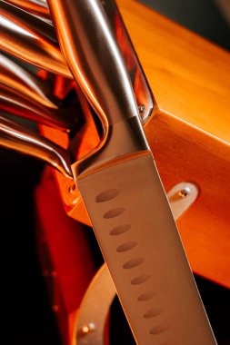 Keskin mutfak bıçağı arka planda diğer bıçaklarla birlikte tahta blokta dinleniyor.