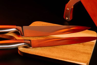 Keskin bıçaklar, geceleri mutfak ortamındaki tahta kesme tahtasının üzerinde durur.