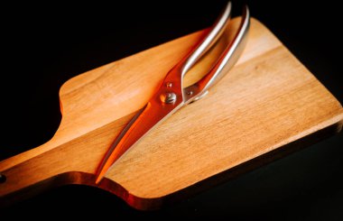 Ahşap kesme tahtasının üzerinde makas dinleniyor.