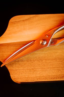 Basit bir mutfak ortamında tahta bir kesme tahtasına yerleştirilmiş metal makas.