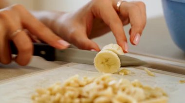 Keskin bir bıçak ve kesim tahtasıyla evde yemek tarifi için muz kesmek.