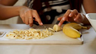 Kadın mutfakta sağlıklı bir şeyler atıştırmak için muzu parçalara ayırıyor.