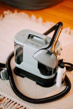 Elektrikli süpürgeyi, ahşap zemindeki bir evde sabun ve suyla temizlemek.