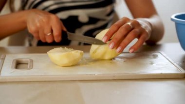 Mutfak ortamında beyaz bir kesme tahtasıyla armut kesmek.